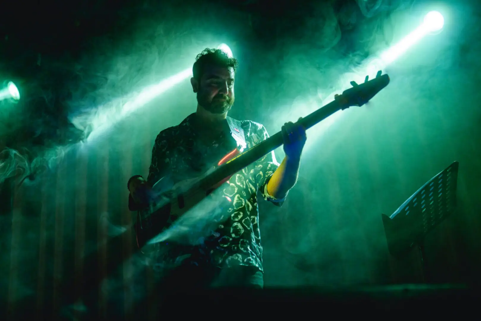 Bassist performing under green stage lights